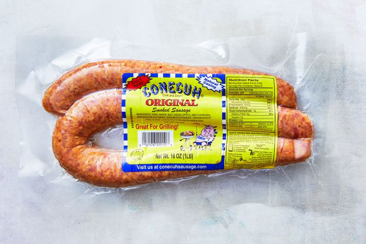 Packaged Conecuh Original Smoked Sausage with a clear vacuum-sealed bag displaying the sausage links and a yellow label highlighting the product's name, "Original Smoked Sausage," and nutritional information.