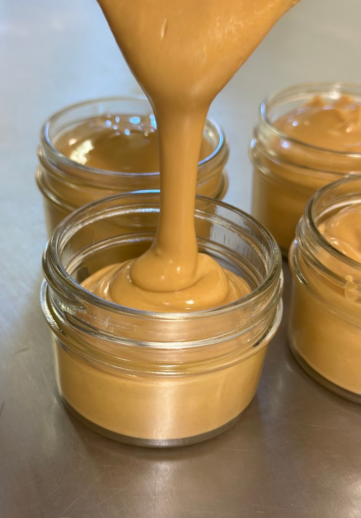 Gluten-free peanut butter being poured into glass jars from Medders Family Farm