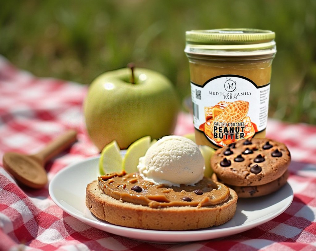 Salted caramel peanut butter dessert with apple slices, ice cream, and cookies on a picnic setting