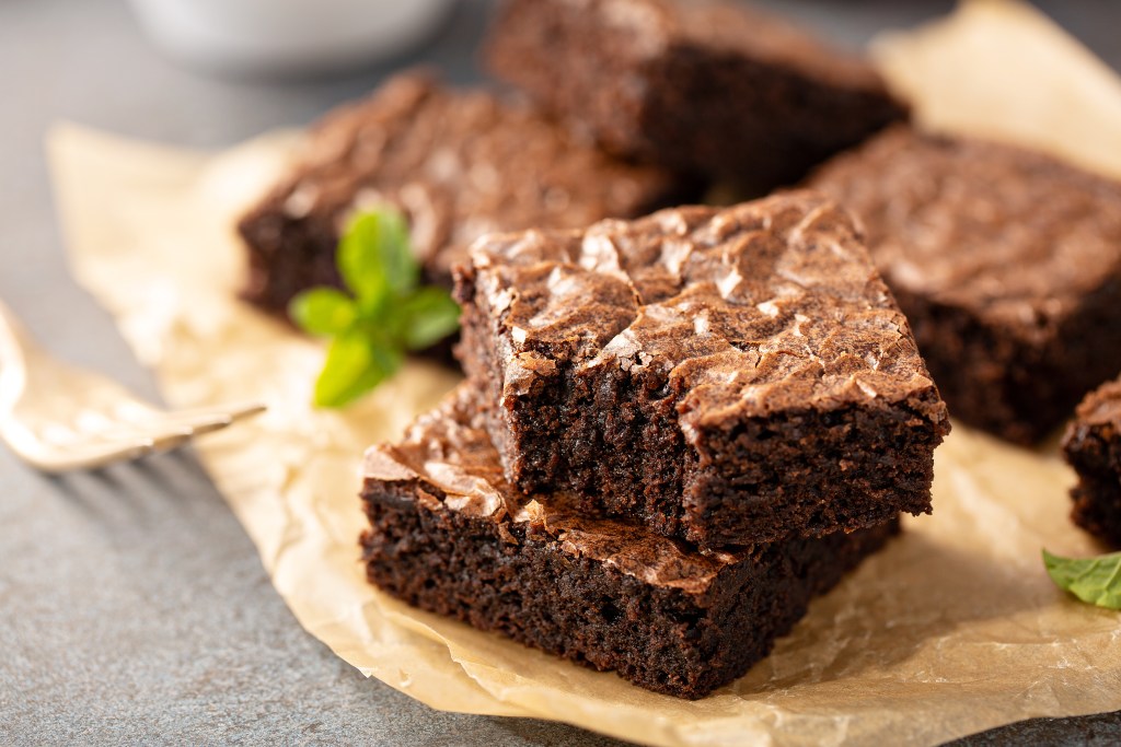 Close-up of rich, fudgy chocolate brownies stacked on parchment paper with a mint garnish