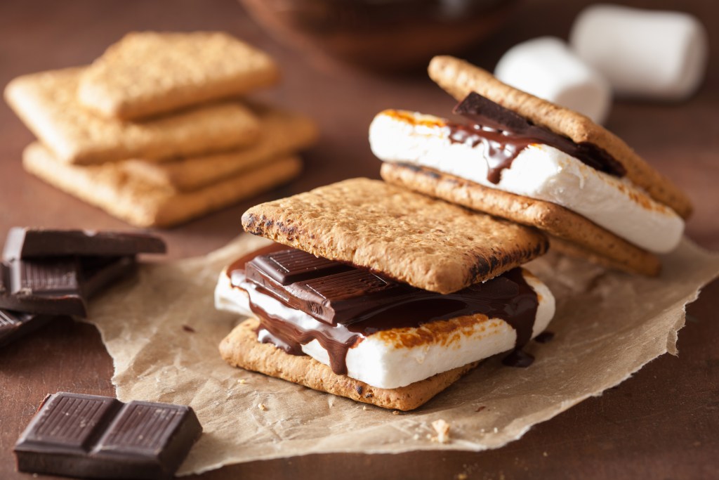 Close-up of classic s’mores made with toasted marshmallows, melted chocolate, and graham crackers on parchment paper