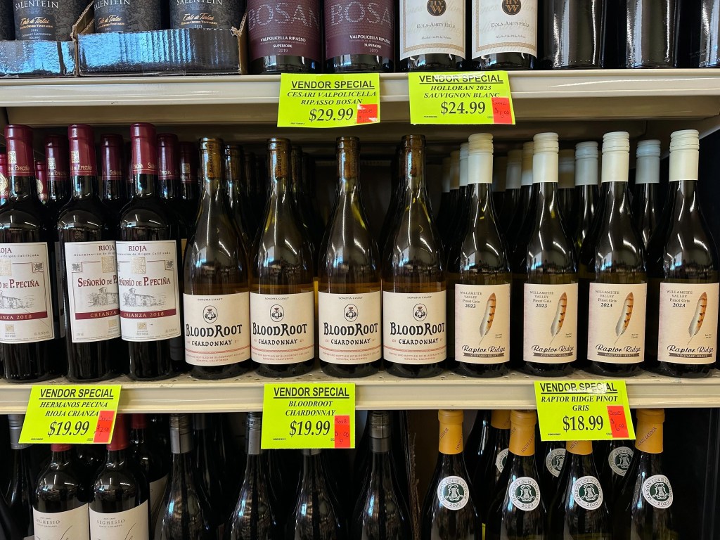 Assorted bottles of wine on display at Piggly Wiggly Birmingham, including BloodRoot Chardonnay and Raptor Ridge Pinot Gris with vendor special pricing