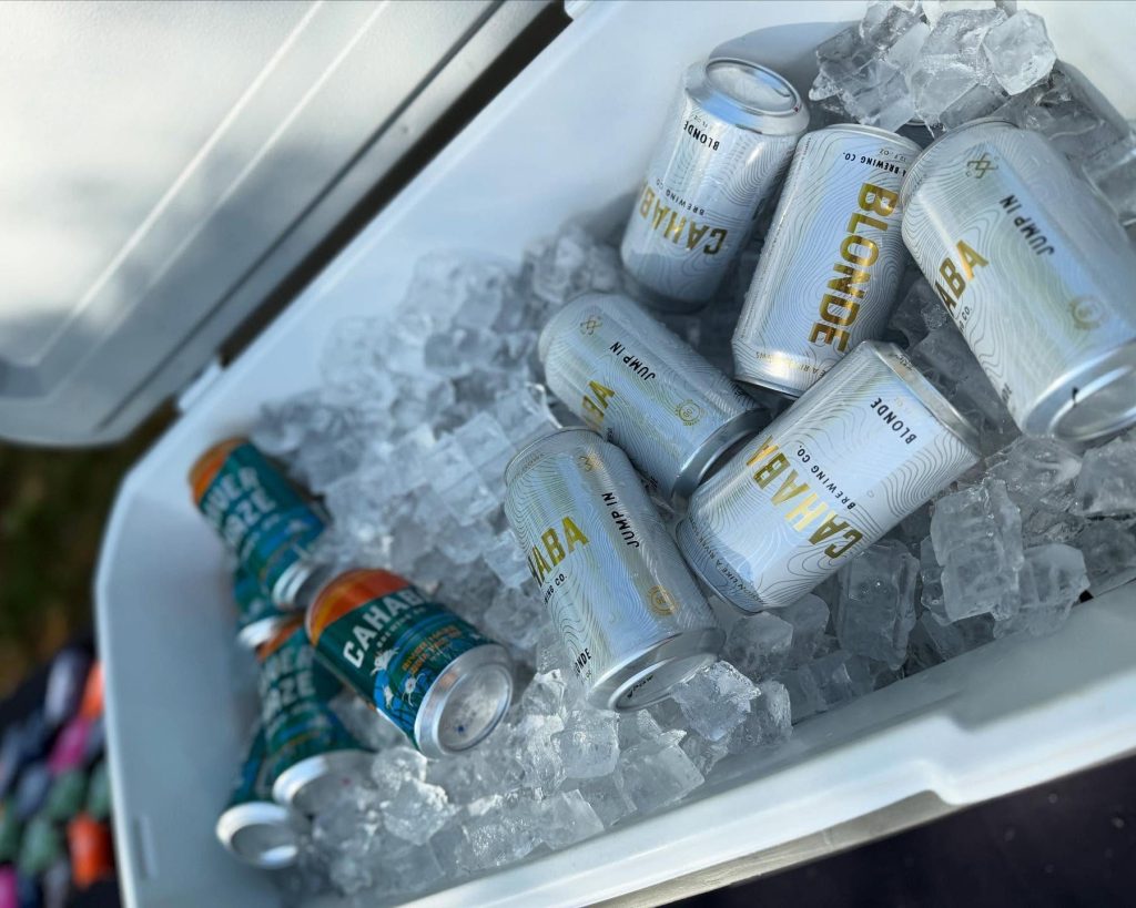 Cahaba Brewing Co Blonde Ale and River Haze IPA cans chilling in a white cooler filled with ice