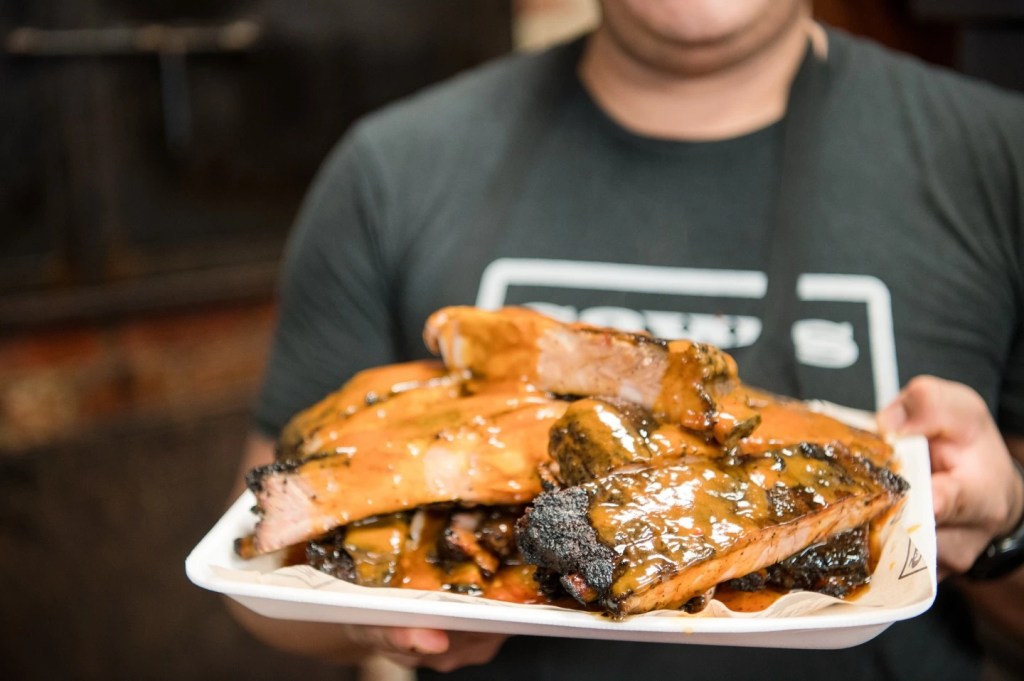 Close-up of smoked barbecue ribs topped with sauce on a tray at Saw’s BBQ in Birmingham Alabama