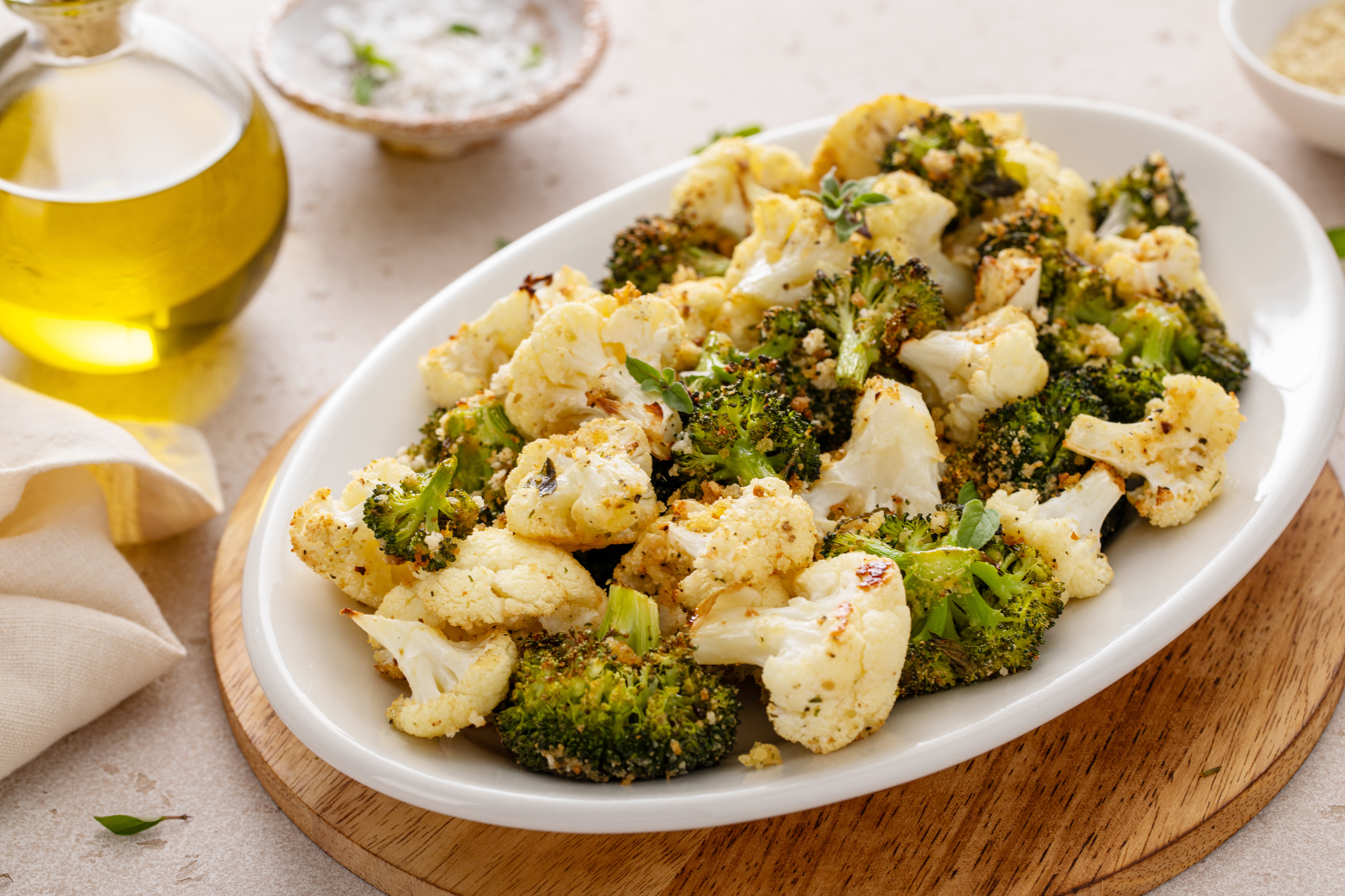 Oven roasted broccoli and cauliflower florets seasoned with olive oil, garlic and herbs on a white serving platter