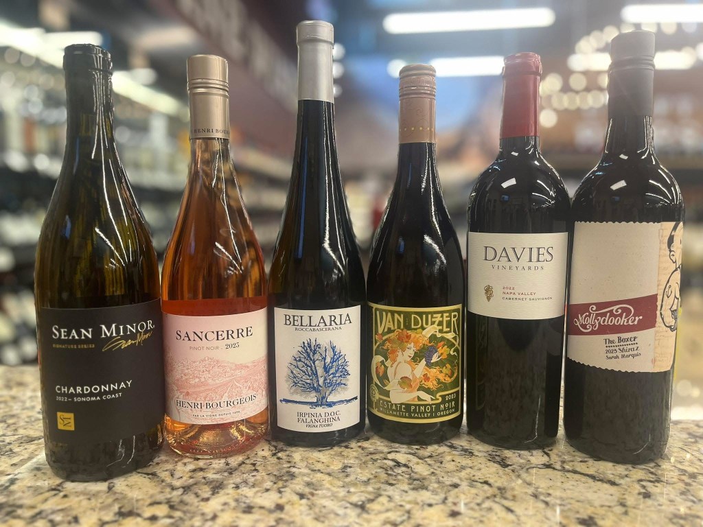 Six wine bottles including Sean Minor Chardonnay Sancerre Henri Bourgeois Bellaria Falanghina Van Duzer Pinot Noir Davies Cabernet Sauvignon and Mollydooker Shiraz displayed on a countertop for a wine tasting