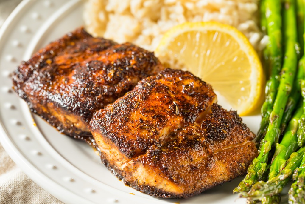 Grilled mahi mahi fillets served with rice asparagus and lemon on a plate