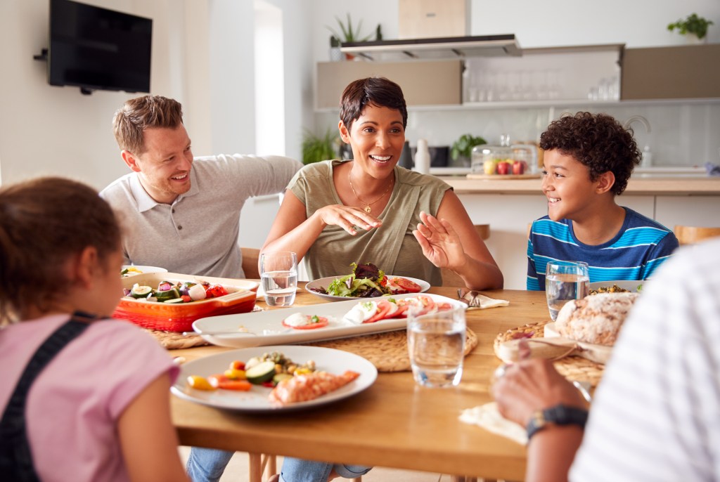 Family enjoying a healthy homemade dinner together at the table with fresh salad vegetables and bread