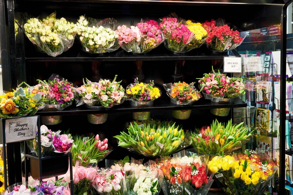 Display of colorful fresh flower bouquets including roses and tulips in a grocery store floral section