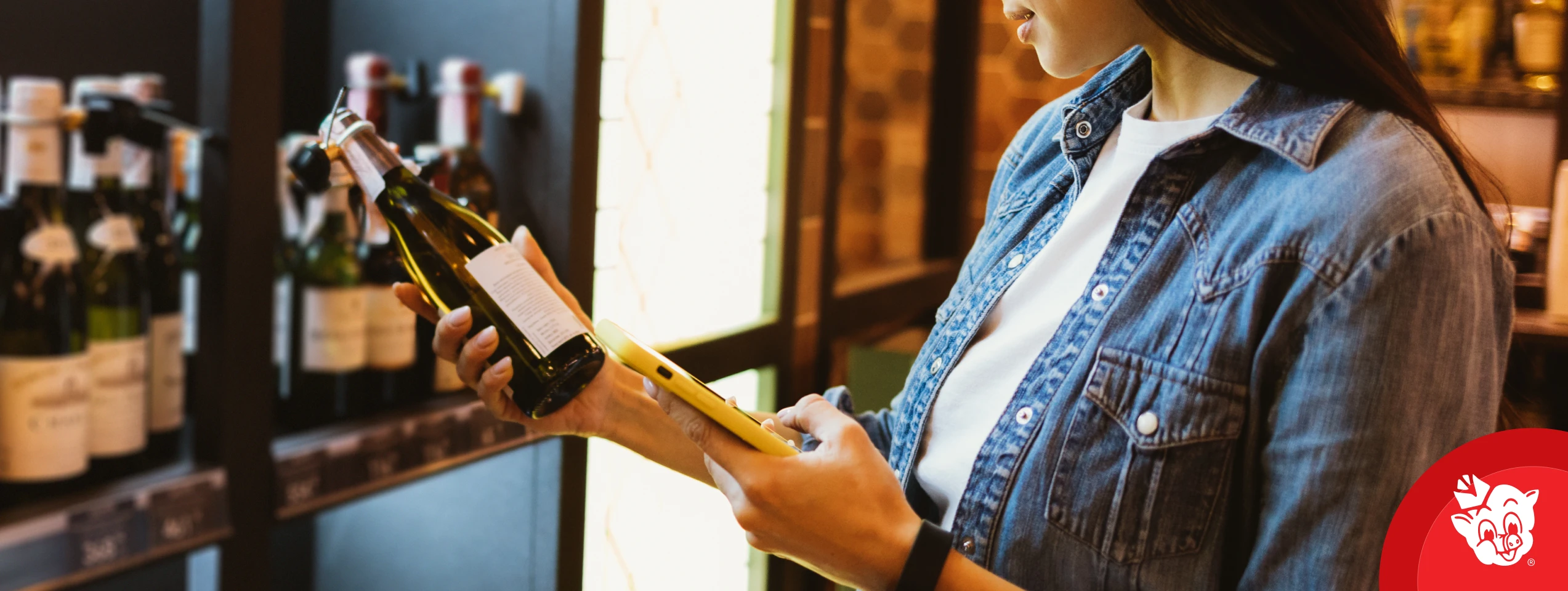 Shopper using a phone to compare wine options in a Piggly Wiggly Birmingham wine aisle