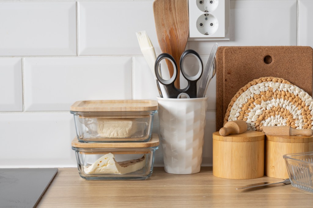 Reusable glass food storage containers and kitchen utensils organized on a countertop for back-to-school meal preparation