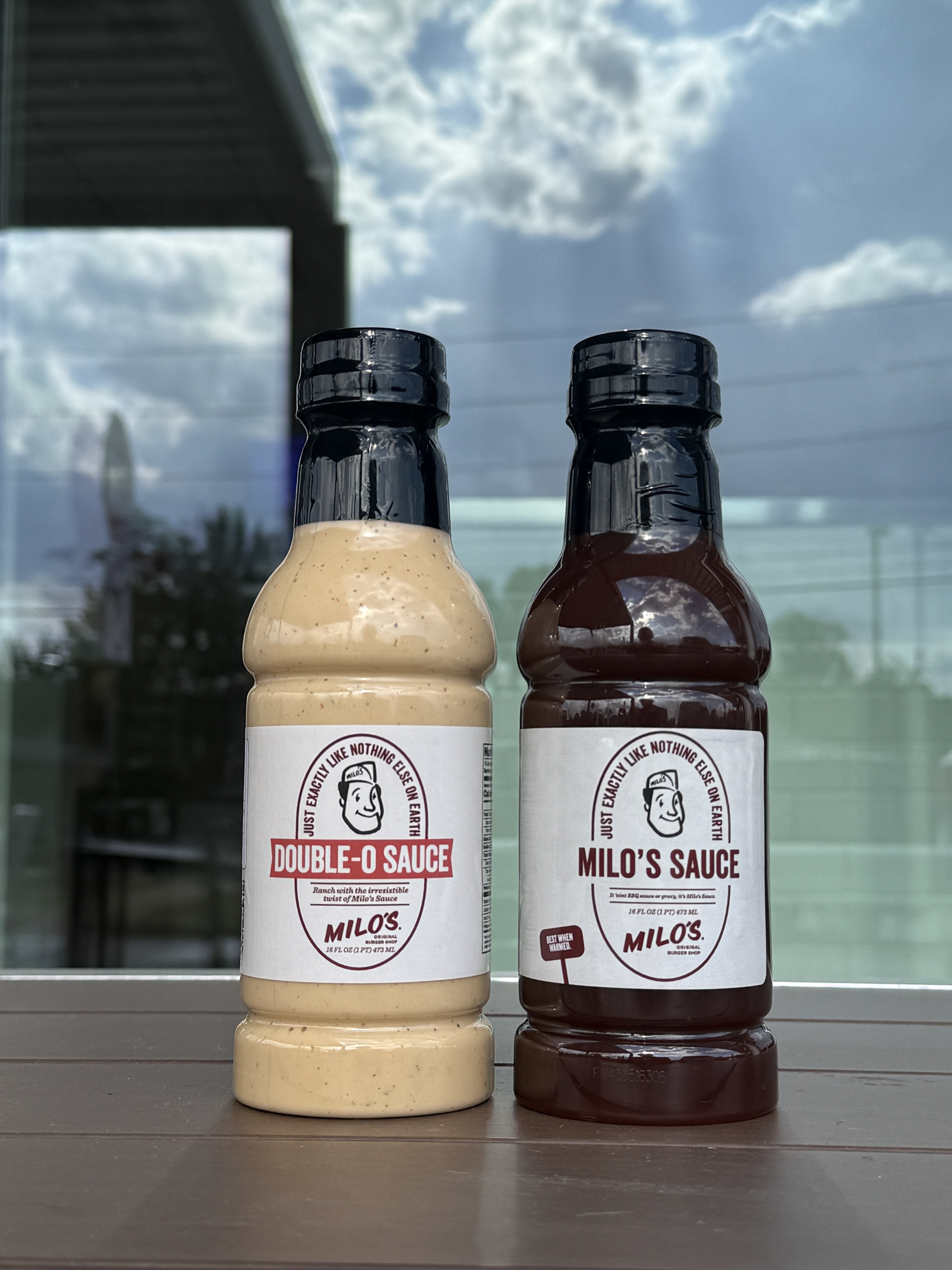 Bottles of Milo’s Double-O Sauce and original Milo’s Sauce standing side by side.